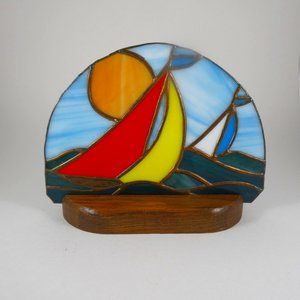 Vintage handmade stained glass sailboats on the water.
